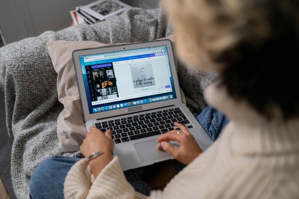 A woman uses a laptop to edit photos while sitting comfortably at home.